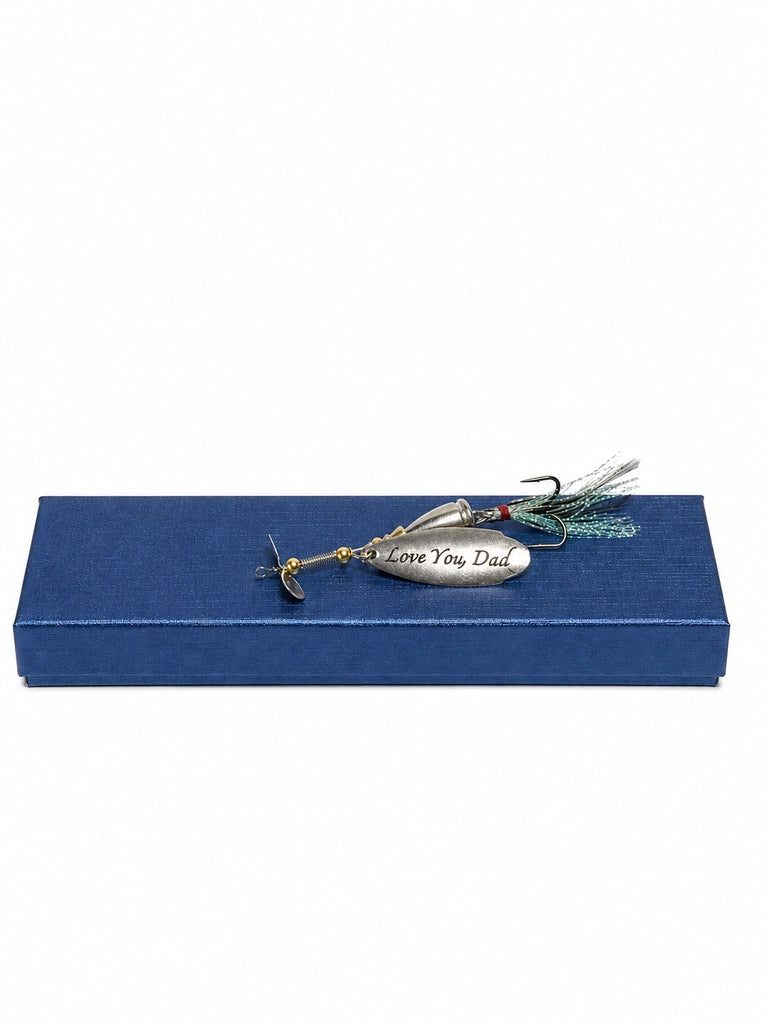 A fishing lure engraved with 'Love You Dad' rests on a textured blue gift box against a plain white background.