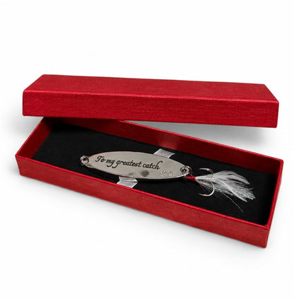 A silver metal fishing lure engraved with 'To my greatest catch.