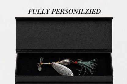 A silver metal fishing lure with a green and red skirt is displayed inside an open black presentation box on a white background, with the text 'FULLY PERSONILZIED' above it.