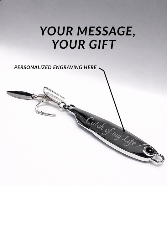 A silver metal fishing lure with hooks attached, shown on a white background with promotional text reading 'YOUR MESSAGE, YOUR GIFT' and 'PERSONALIZED ENGRAVING HERE.' The lure has engraved text on its body.