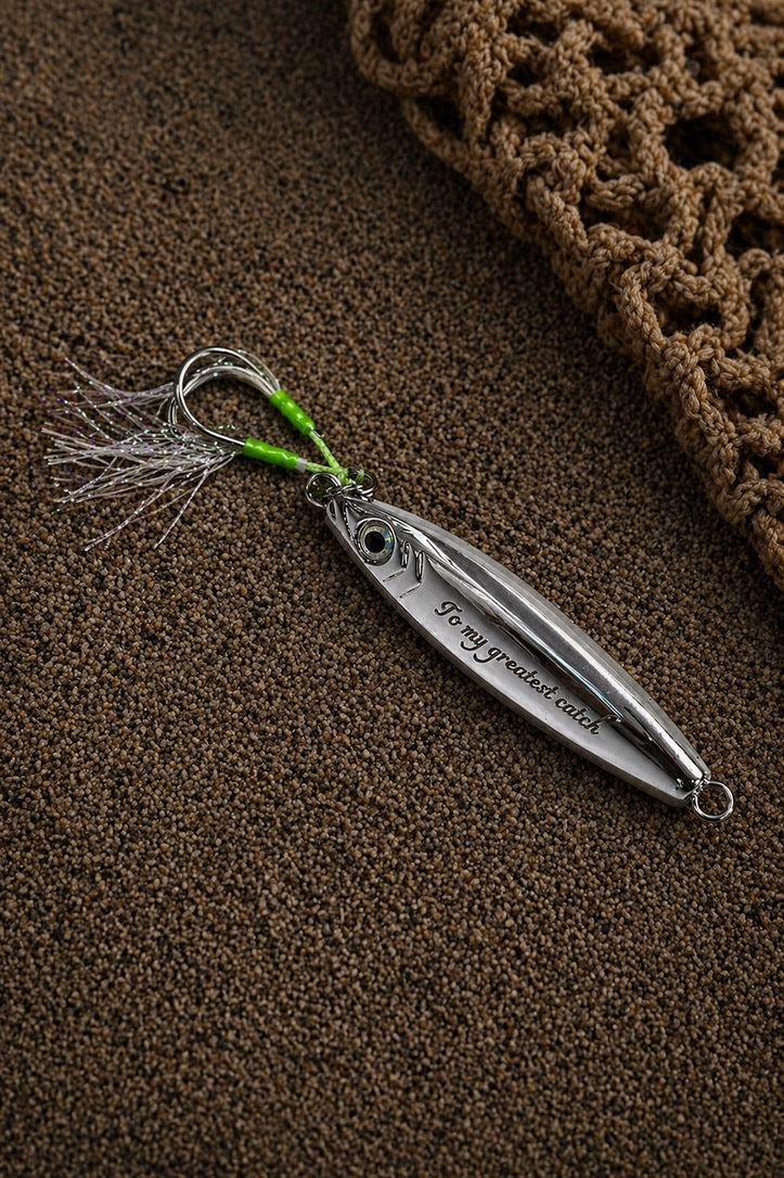 A silver metal spinnerbait fishing lure with a bright green and silver skirt, resting on a brown textured surface next to a brown crocheted item.