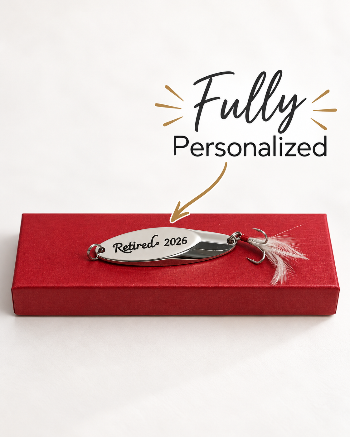 A silver metal fishing lure engraved with 'Retired 2026' resting on a red gift box, with the text 'Fully Personalized' and an arrow above it.
