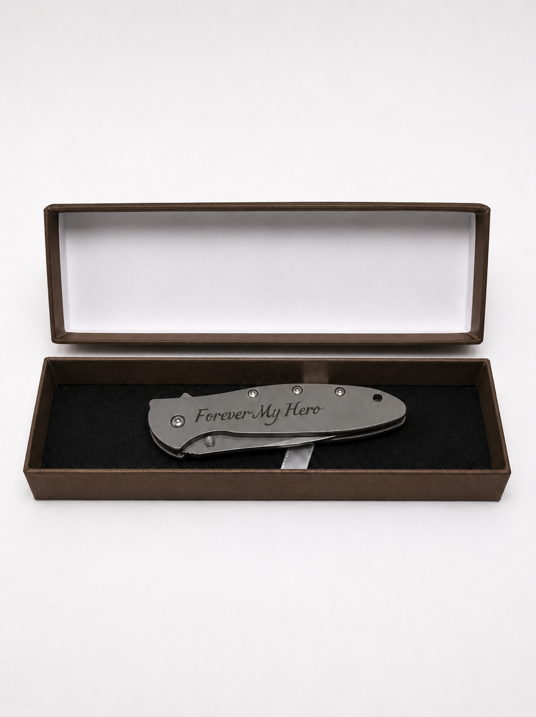 A folding pocket knife with 'Forever My Hero' engraved on the handle, presented inside an open brown gift box with a black velvet insert on a white background.