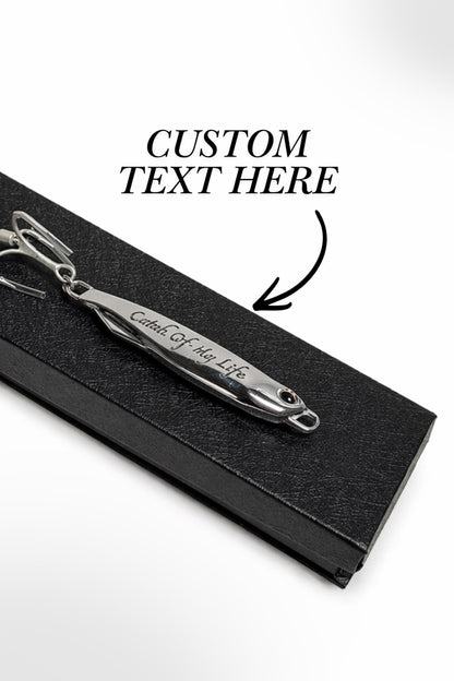 A silver metal keepsake pendant engraved with 'Crown Of My Life' resting on a black textured display box. Black text overlay reads 'CUSTOM TEXT HERE' with an arrow pointing to the engraving.