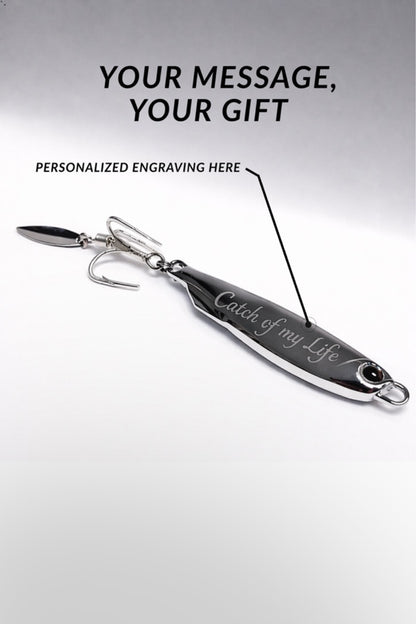 A silver metal fishing lure with a hook and blade, shown on a light gray background with promotional text reading 'YOUR MESSAGE, YOUR GIFT' and 'PERSONALIZED ENGRAVING HERE.' The lure has engraved script text on its body.