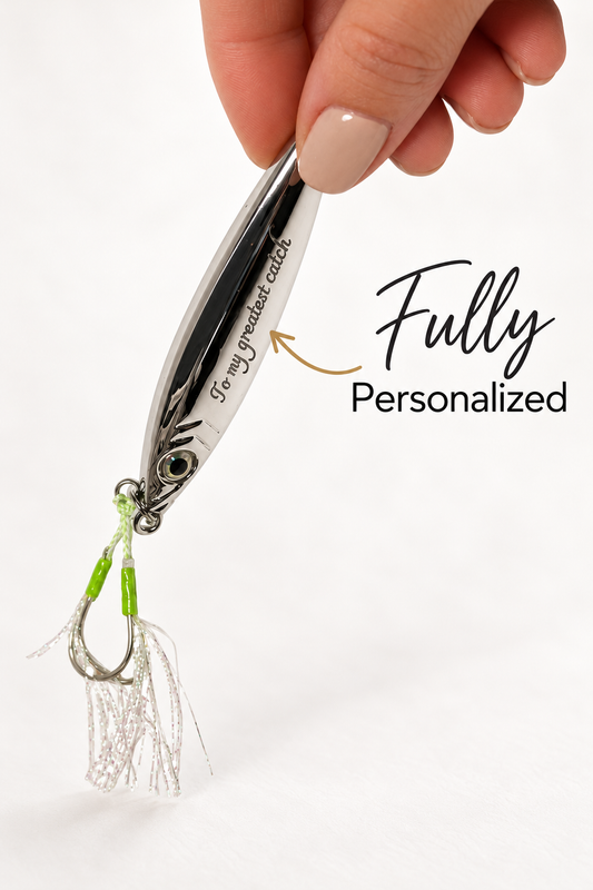 A close-up of a hand holding a silver metal fishing lure with a treble hook and white skirt. The lure has black and white striping with green accents near the hook.