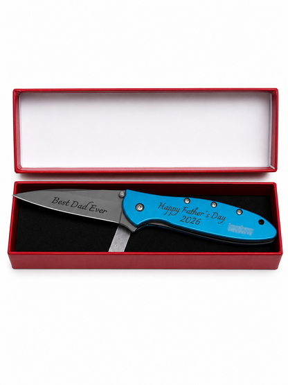 A personalized folding pocket knife with a bright blue handle and a silver blade, presented inside an open red gift box with a white interior. The handle is engraved with 'Happy Father's Day 2026' and the blade is engraved with 'Best Dad Ever'.